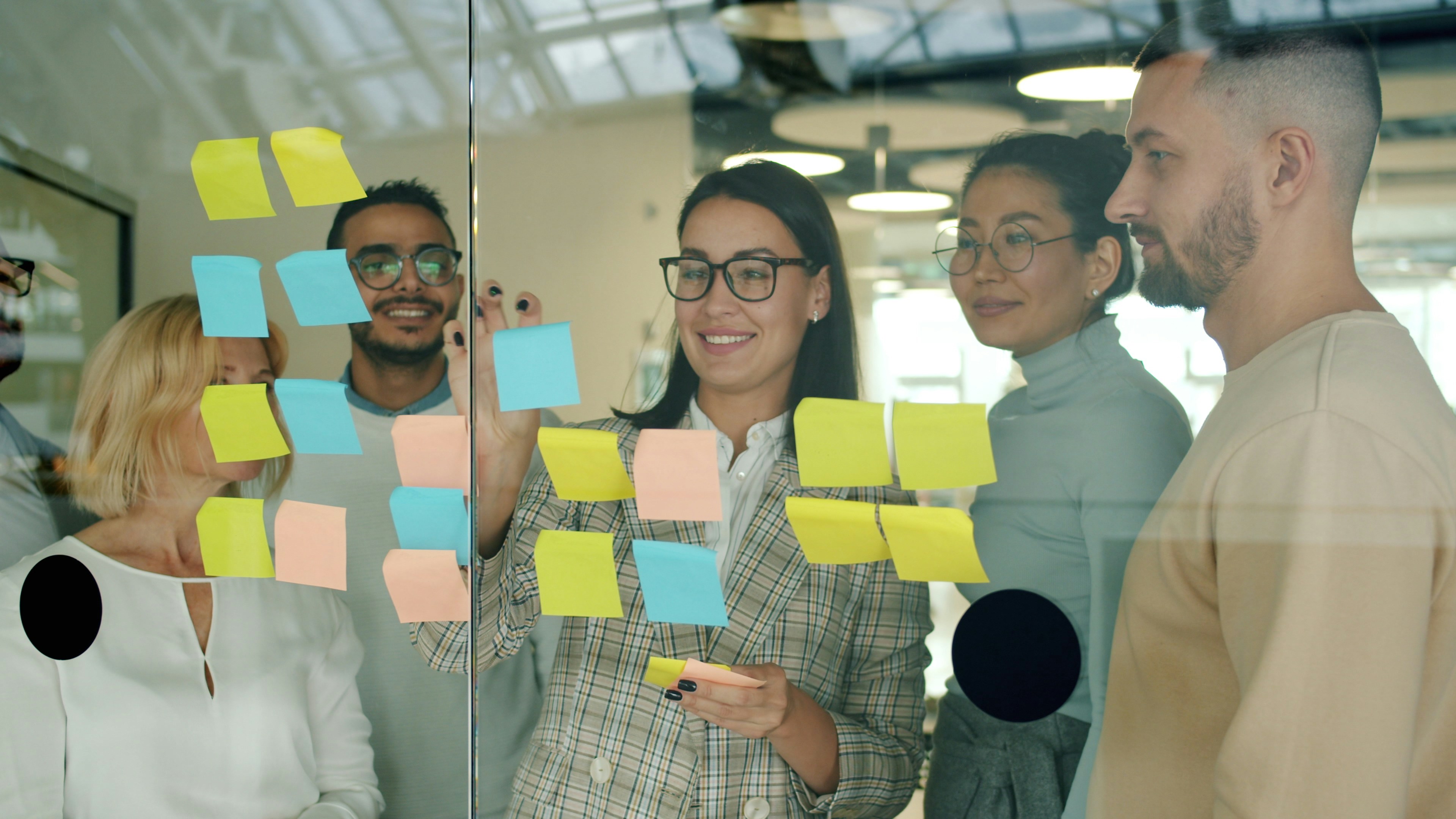 A team working with sticky notes on a glass wall